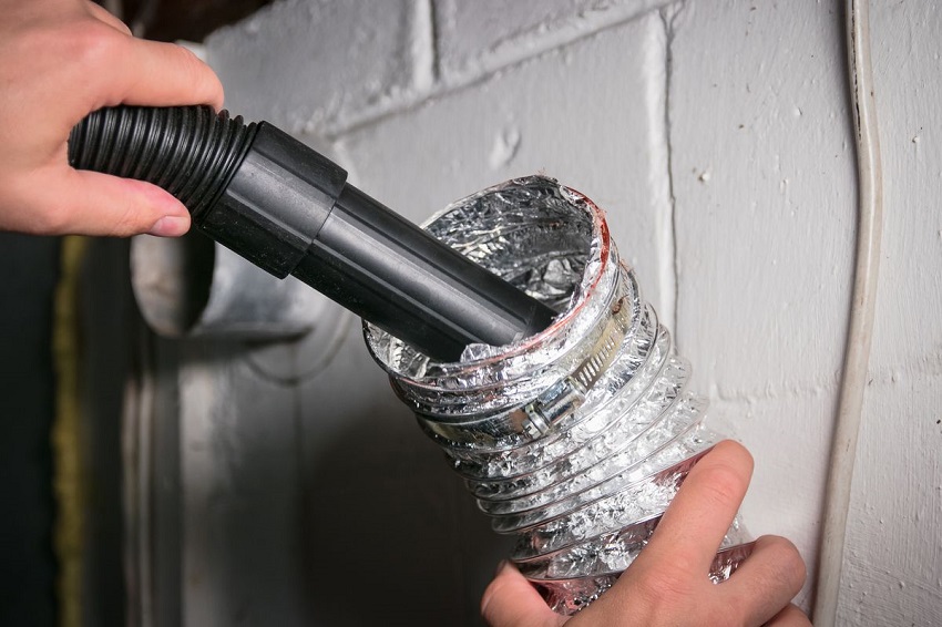 Man using vacuum hose for dryer vent cleaning