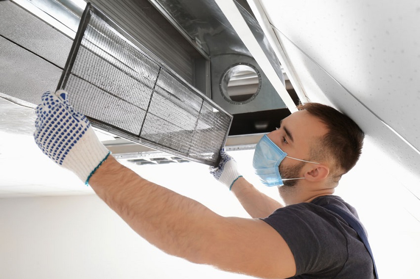 Professional air duct cleaning technician removing dirty air duct filter