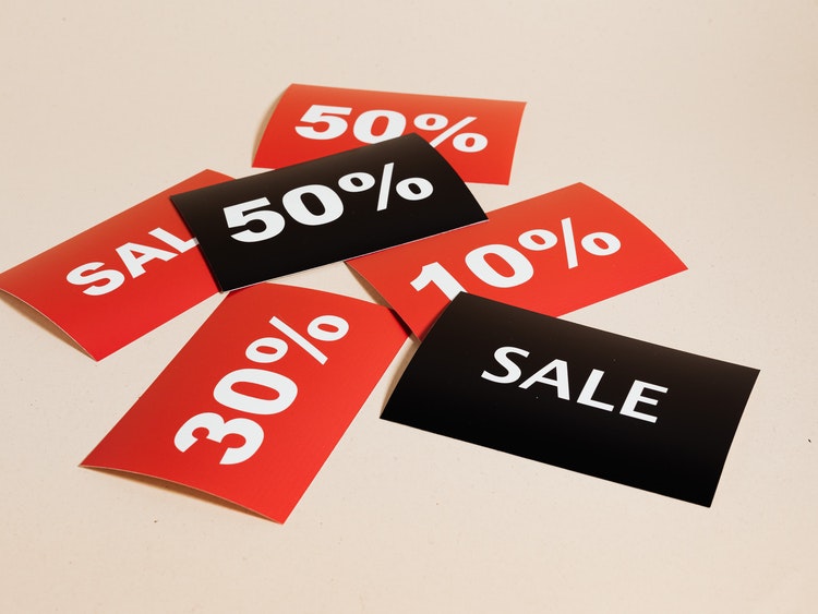 Red and black discount tags labelled 'sale,' '10%,' '30%' and '50%' on flat white surface