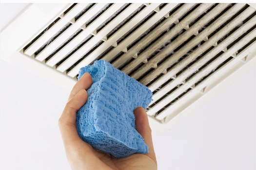Cleaning white indoor vent cover with blue sponge