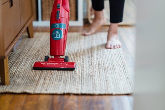 Barefoot woman vacuuming beige rug with red vacuum