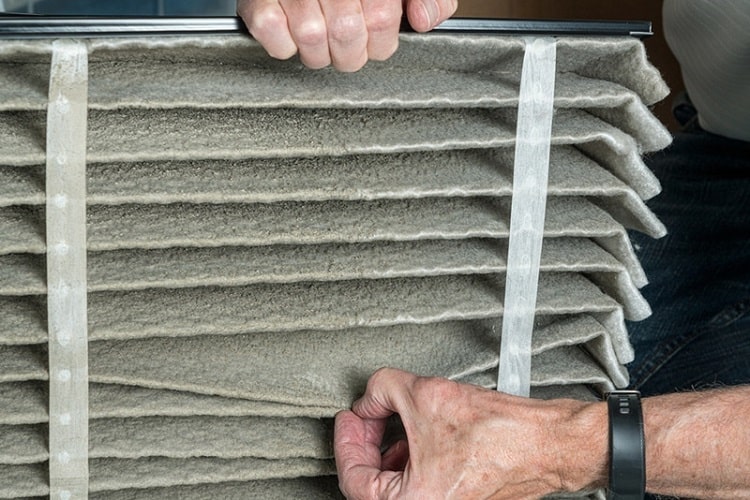 Professional air duct cleaning technician replacing dirty HVAC filter
