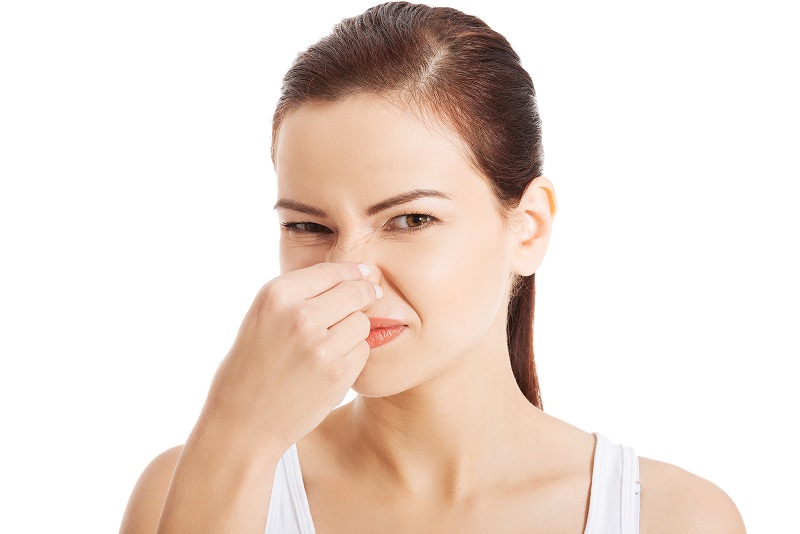 Woman holding nose to avoid smelling musty odor
