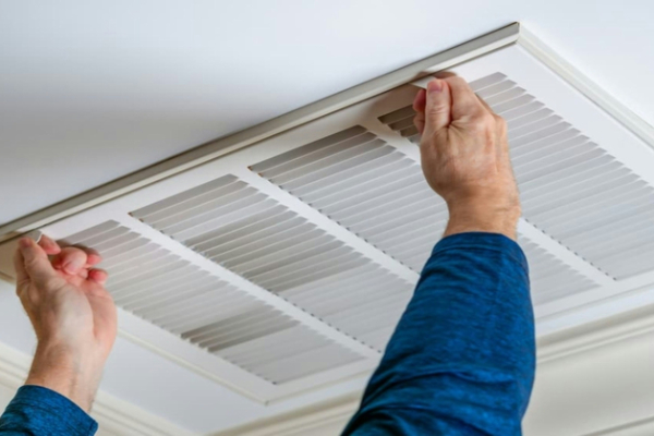 HVAC technician examining a ceiling vent for black dust issues